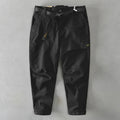Men's loose-fit khaki cotton overalls with a mid waist and elastic fabric, shown laid flat.