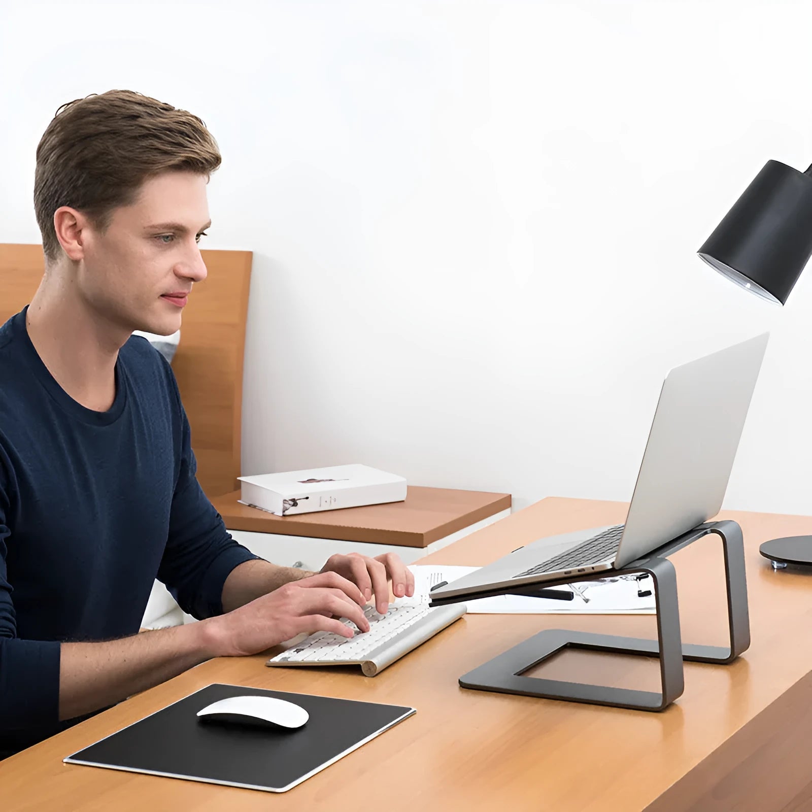 Black aluminium alloy laptop stand on a desk, showing its size and solid base plate.