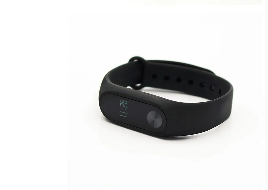 Black Xiaomi Mi Band 2 fitness tracker on wrist showing OLED screen with heart rate data.