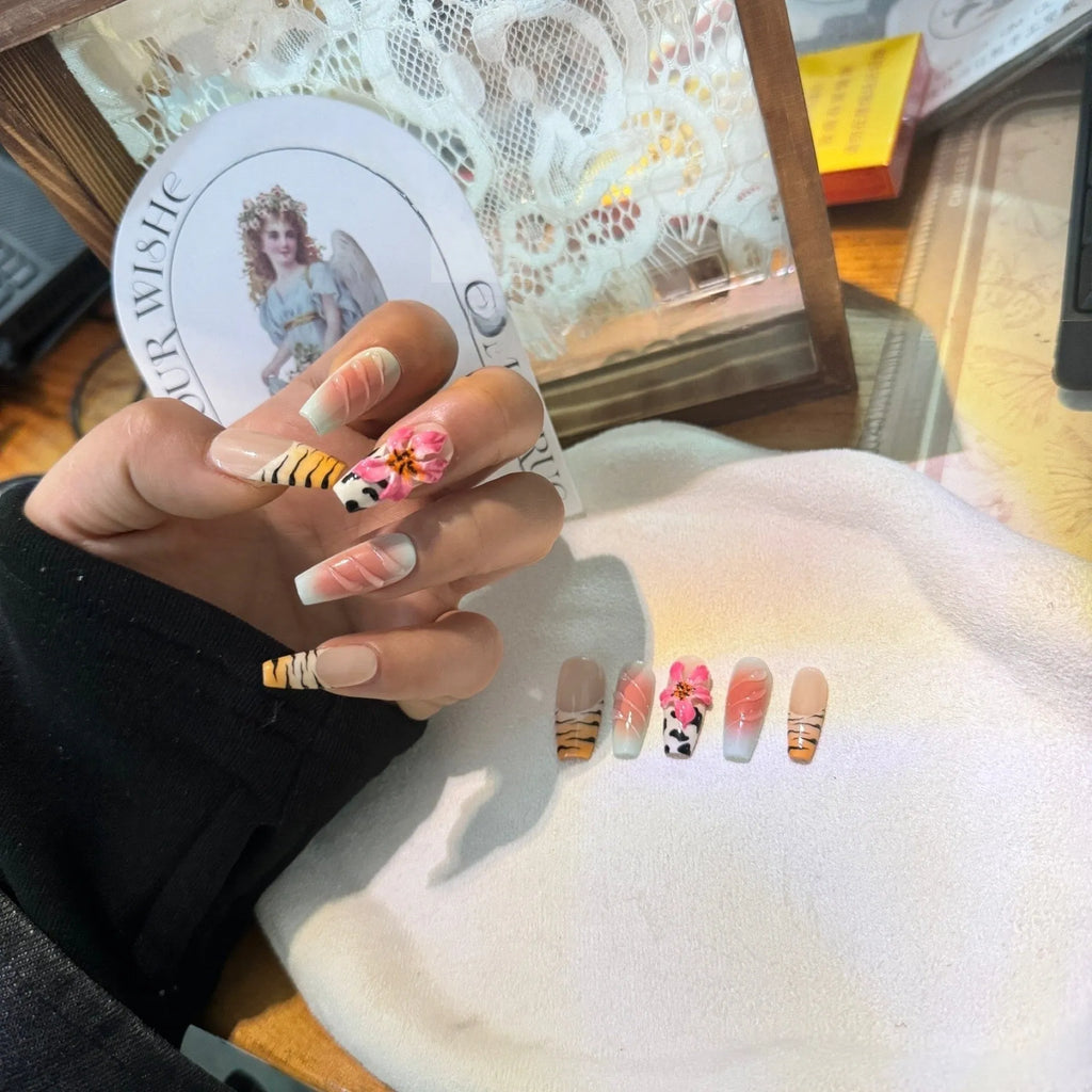 Hand-carved zebra pattern and lily design nail art pieces in four sizes on a clear background.