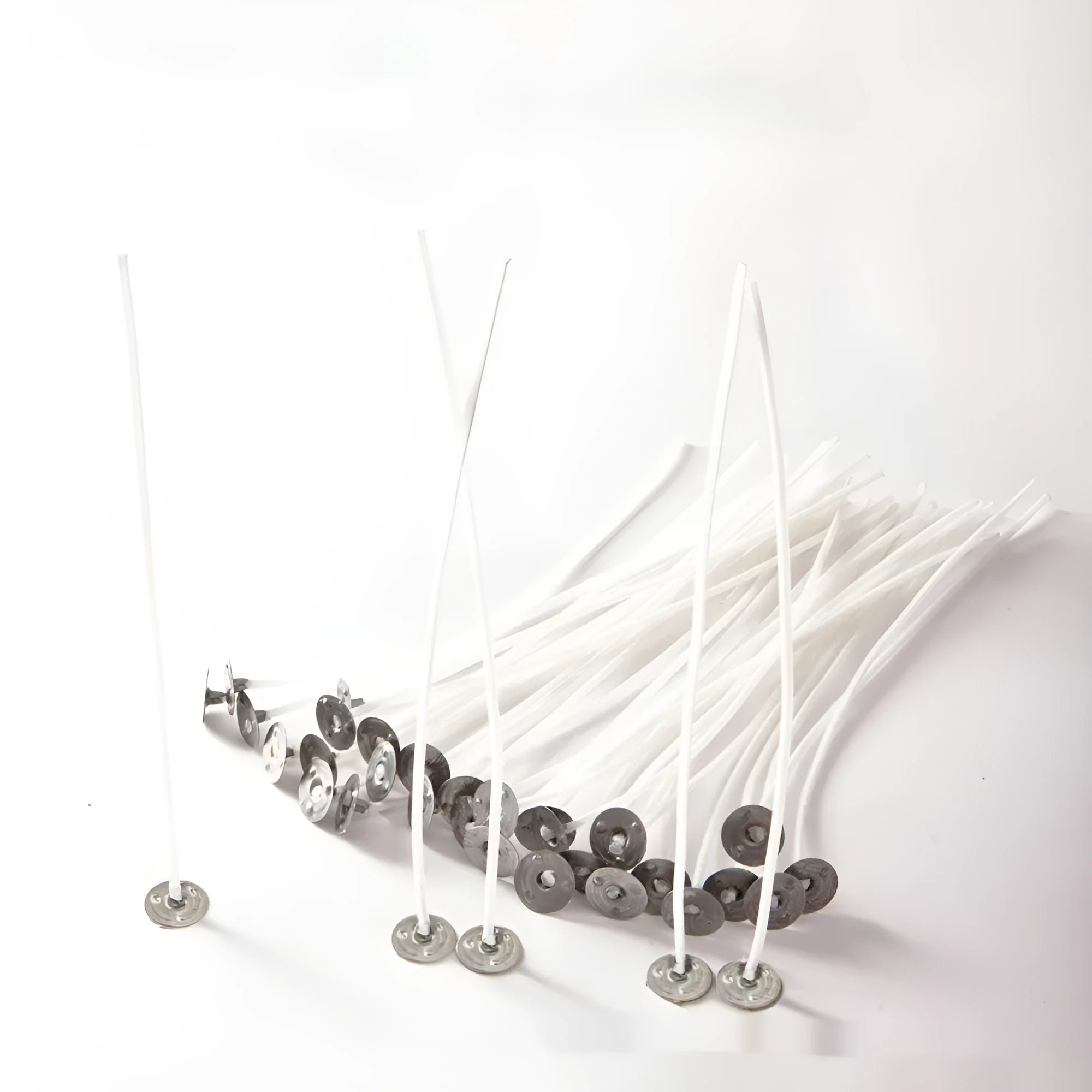 Close-up of white cotton candle wicks in three lengths: 2.6cm, 6cm, and 8cm.