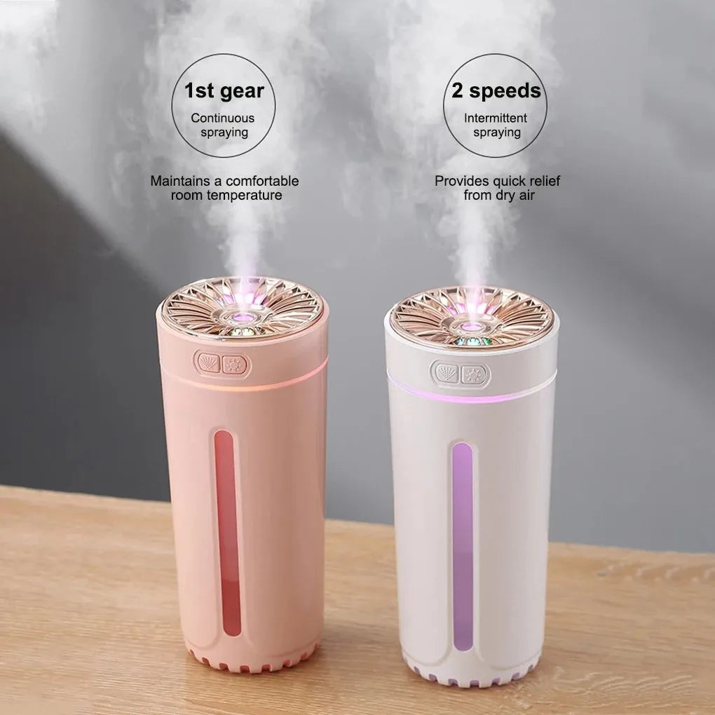 Black wireless ultrasonic humidifier with colourful lights, shown next to a USB cable on a desk.