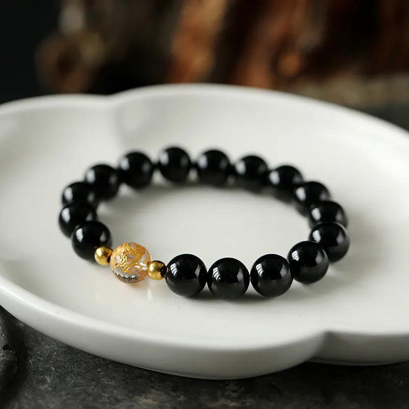 Geometric obsidian black agate white crystal bead bracelet with gold dragon charm on wrist