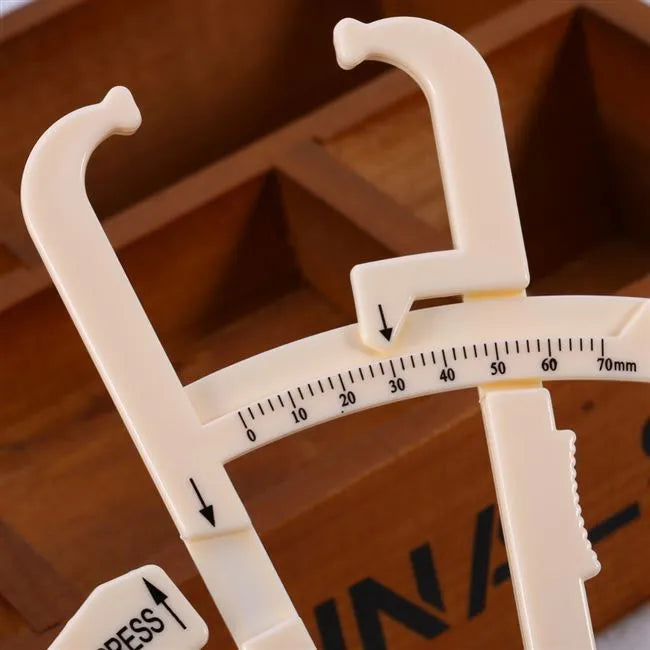 Clear acrylic skin fold fat caliper for body fat measurement showing measurement scale.
