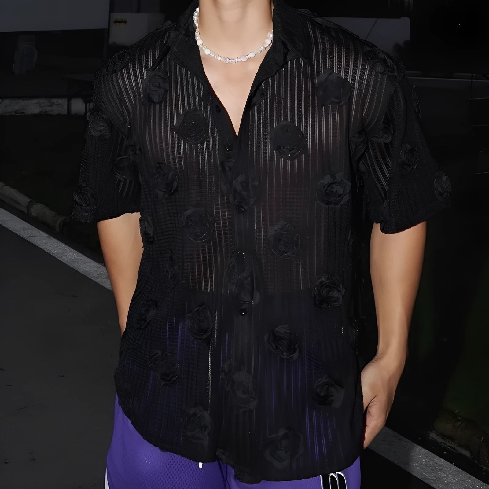 Man wearing a loose-fit black short-sleeved shirt with a large white three-dimensional floral print.