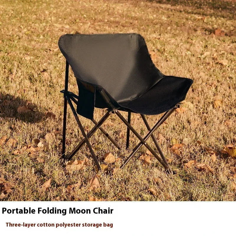 Beige folding camping chair with reclined back and steel frame on grass.