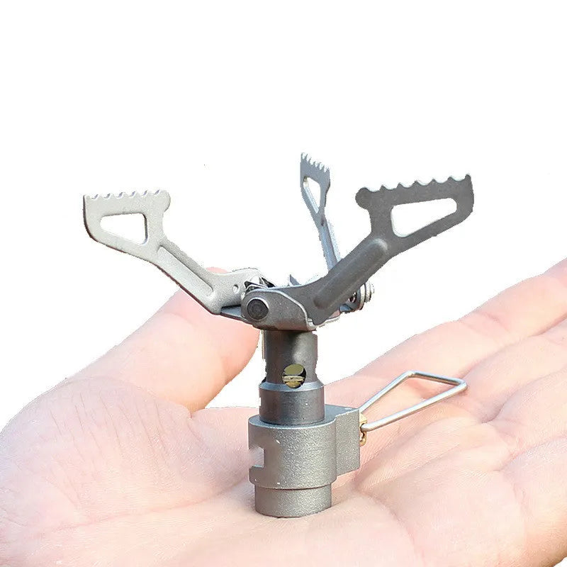Portable metal camping gas stove with a one-piece burner, shown on a flat surface.