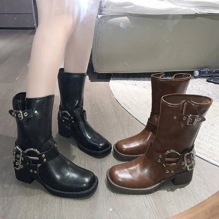 Women's black mid-calf platform boots featuring a large belt buckle on the shaft.