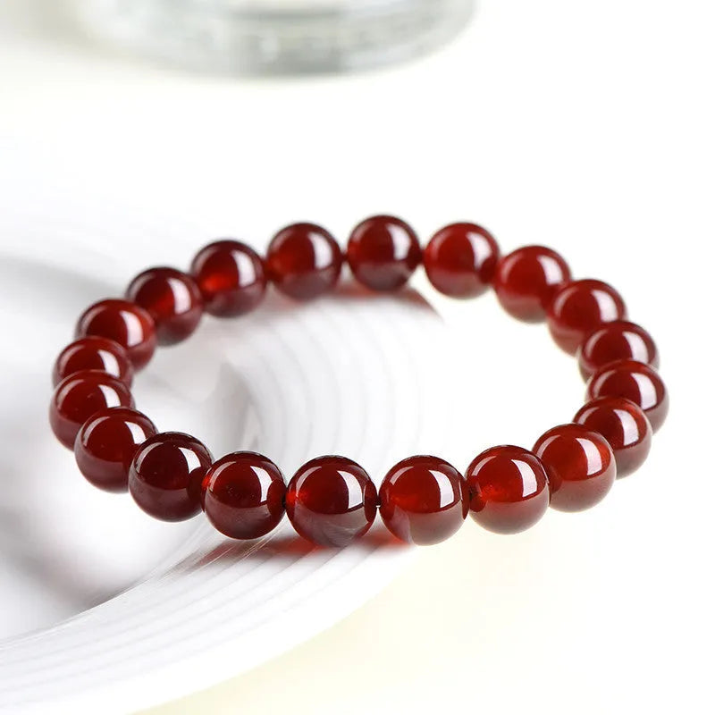 Natural Orange Red Garnet ball bracelet with a Ruyi charm on a white background