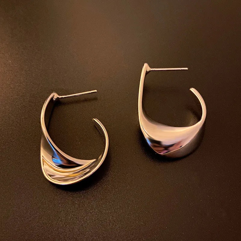 Geometric metal earrings with twisted design and round elements in gold electroplated finish