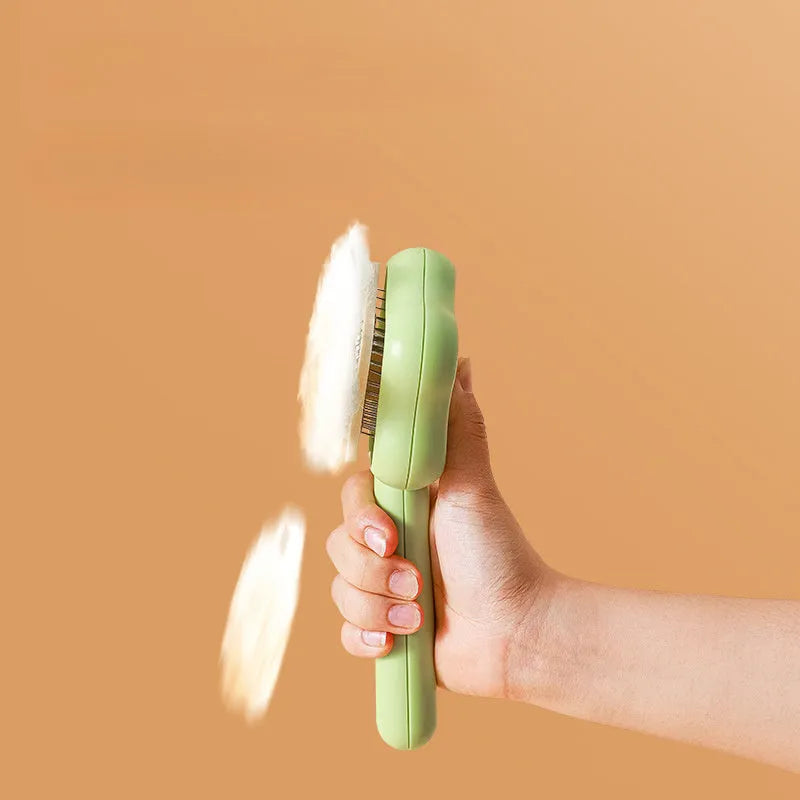 Green stainless steel cat comb with magic wand self-cleaning mechanism showing needle teeth and plastic handle