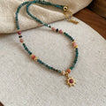 Stone sun pendant freshwater pearl necklace with gold blue pink chain on display.