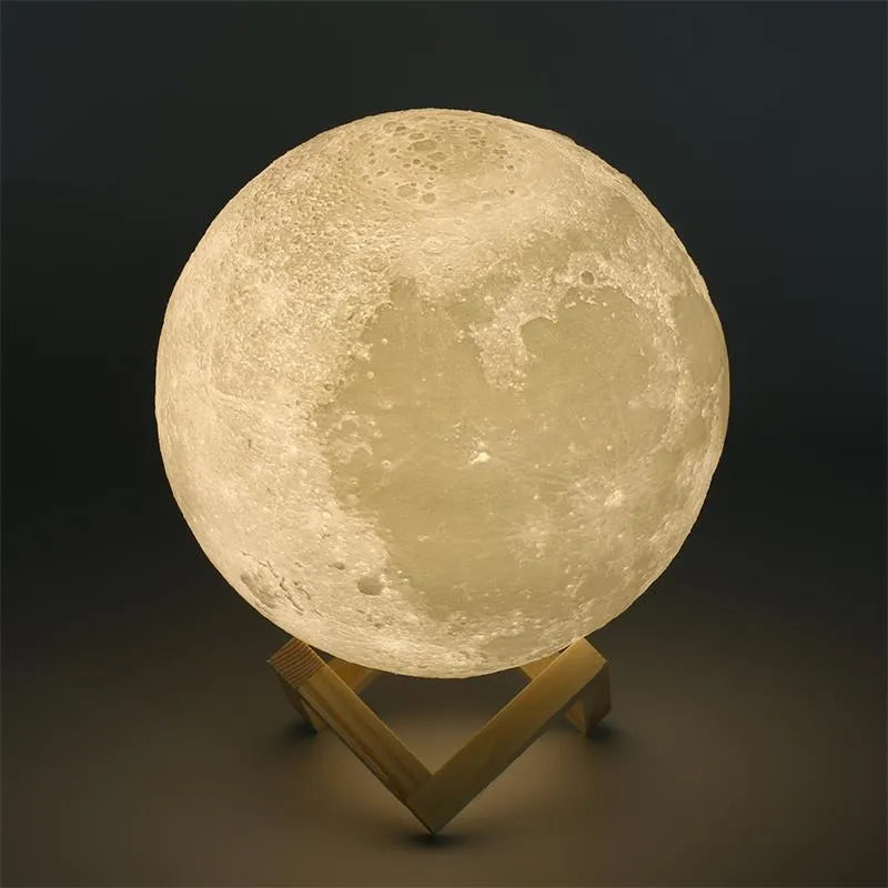3D printed white moon lamp with detailed craters on a wooden stand, glowing with soft yellow light.