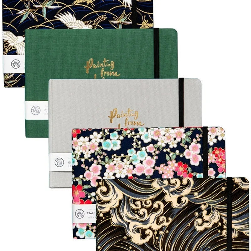 Feiluniao fabric cover watercolour notebook open on a table with brushes, 185mm length