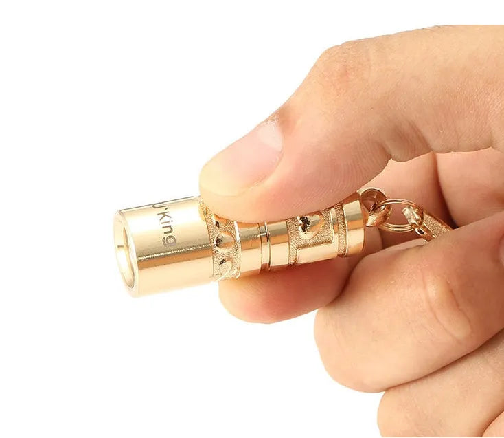 Gold-coloured waterproof zinc alloy portable LED flashlight on a keychain ring.