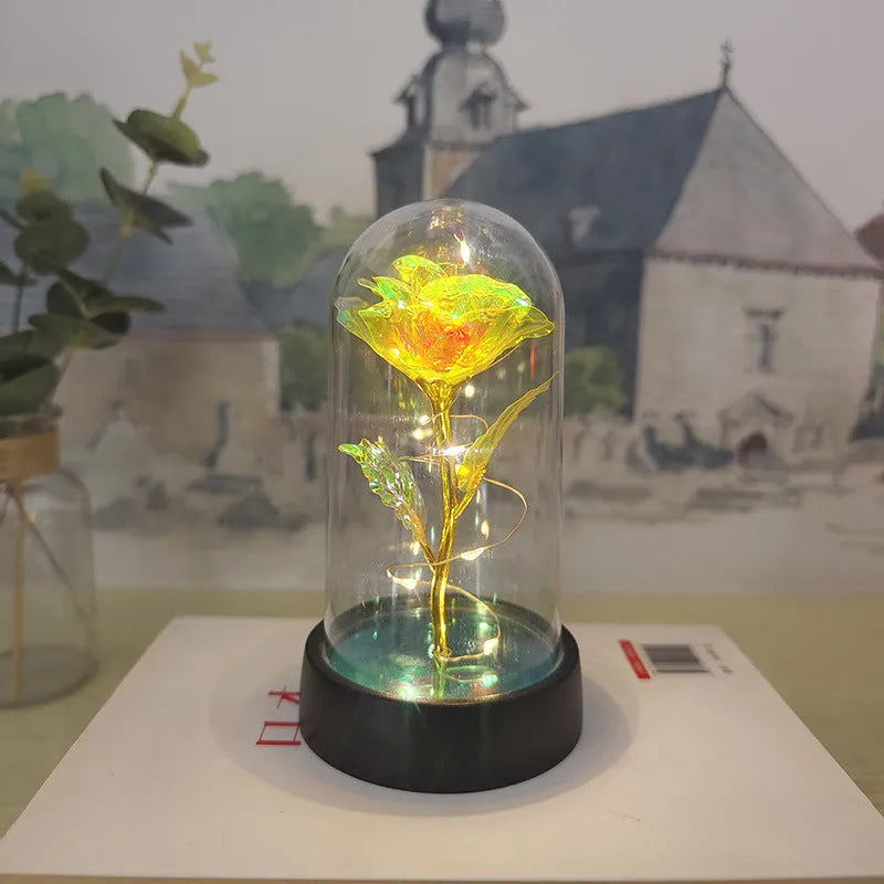 Small decorative night lamp with glass cover and plastic flowers, showing coloured light illumination.