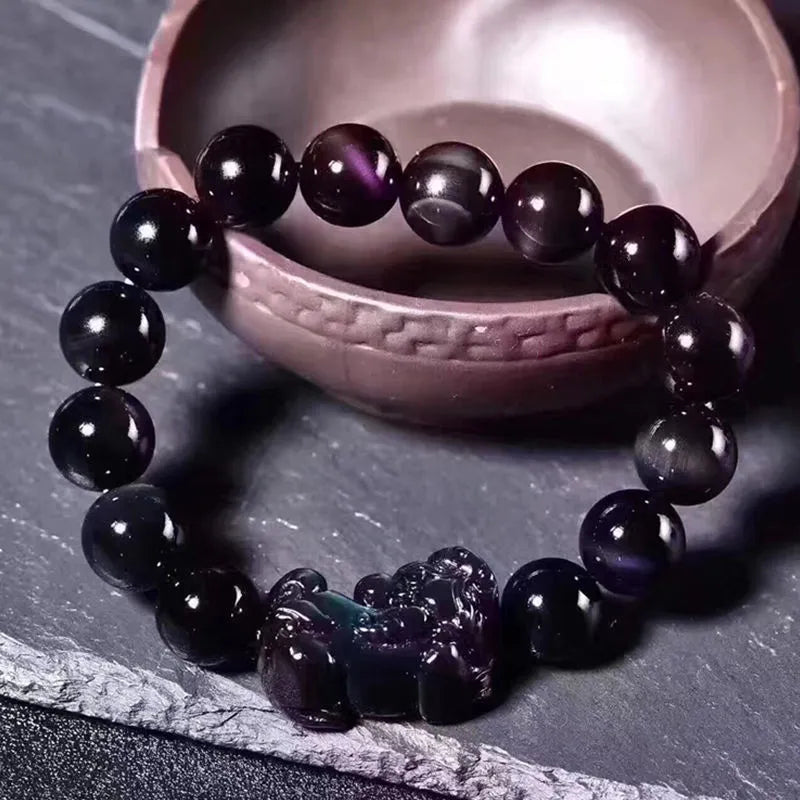 Natural ice colour eye obsidian crystal bracelet on a wrist, showing polished beads on an elasticated band.