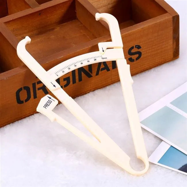 Clear acrylic skin fold fat caliper for body fat measurement showing measurement scale.