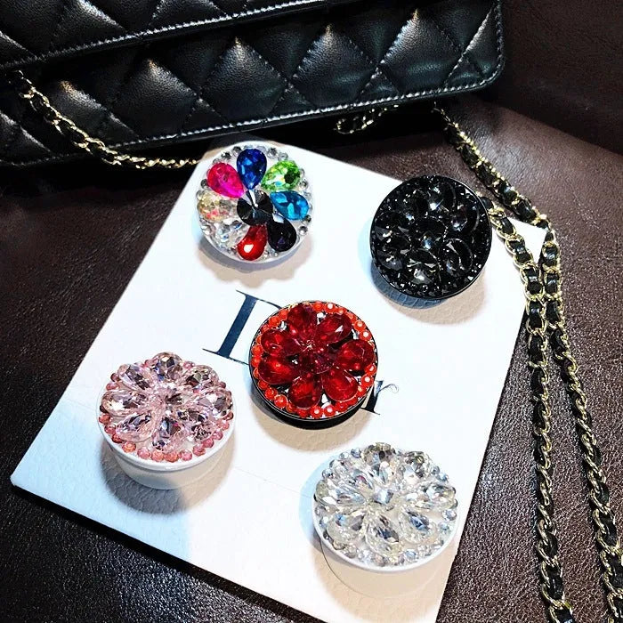 Rhinestone airbag mobile phone holder with telescopic bracket, shown in one of seven colour options for hands-free viewing.