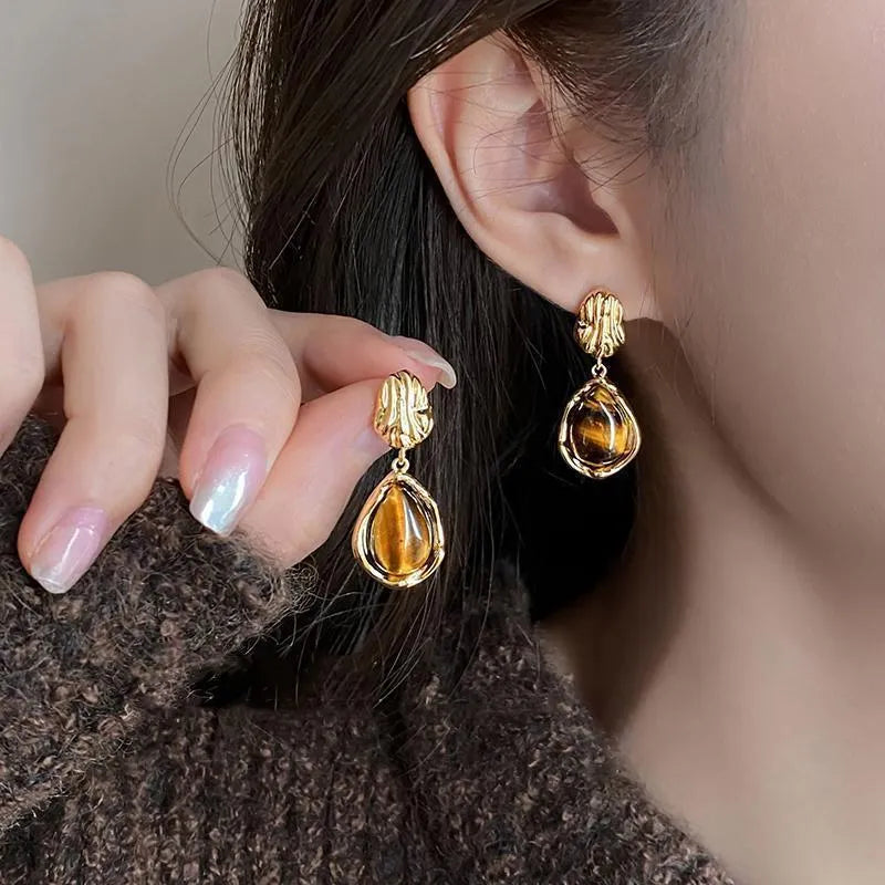 Set of three geometric handmade alloy earrings with tassels on a white background.