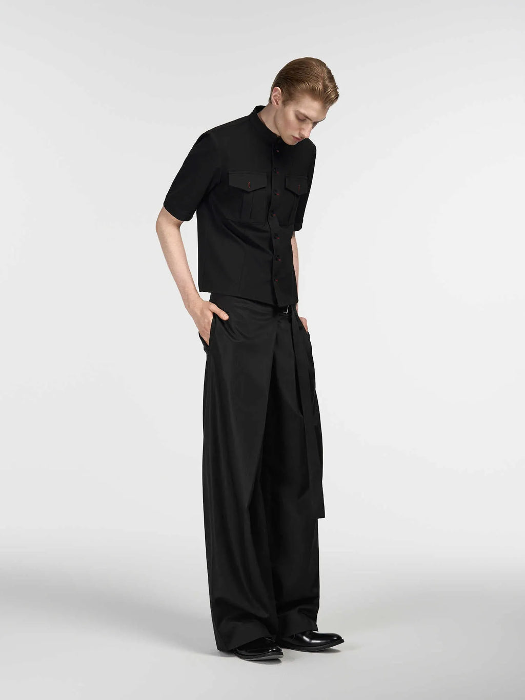 Black straight-leg trousers with a single pleat and adjustable waistband, laid flat.