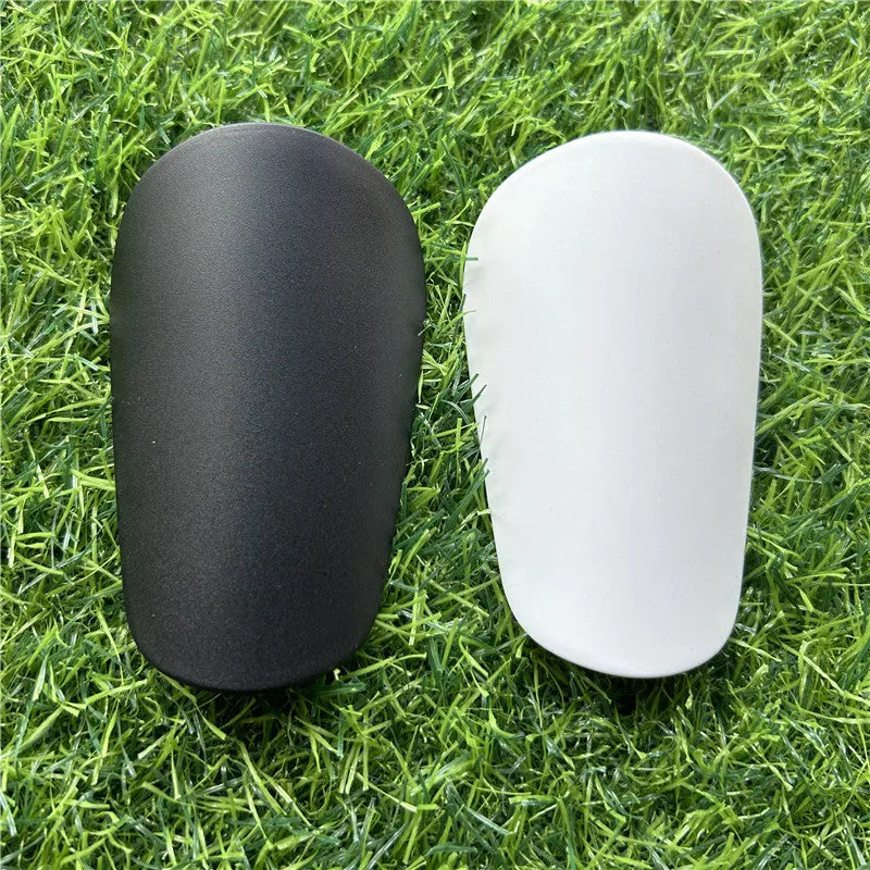 Extra small plastic football shin guards in black and white, measuring 8x5cm