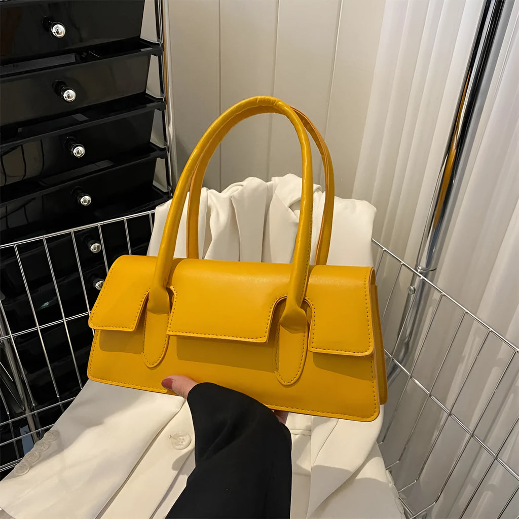 Women's black PU leather small square shoulder bag with stitching detail on a table.