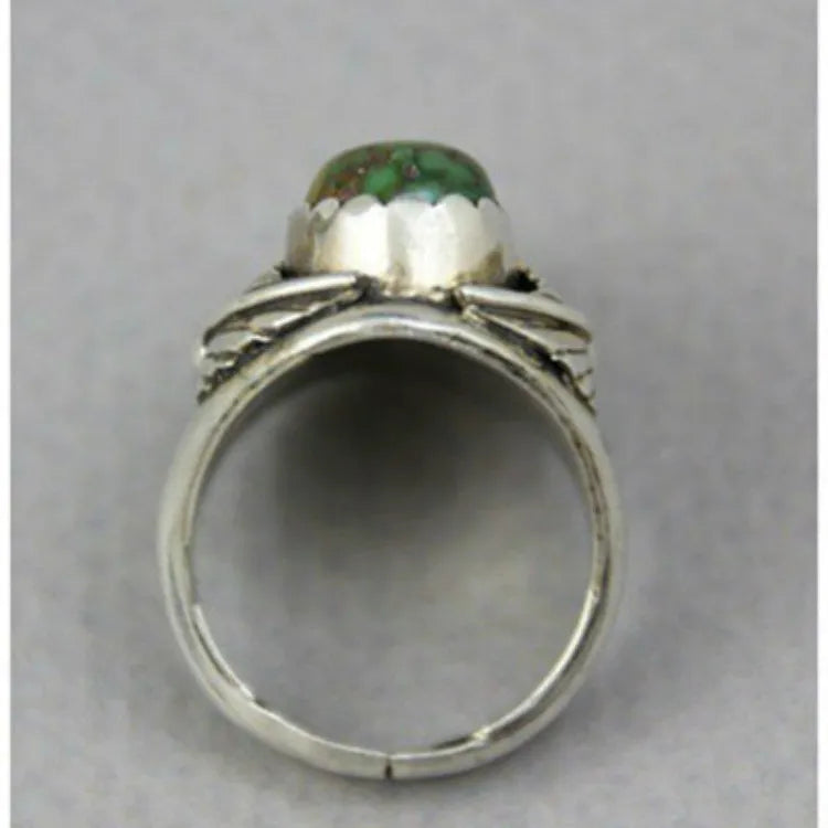 Close-up of a women's turquoise geometric ring with a retro inlaid design on a finger.