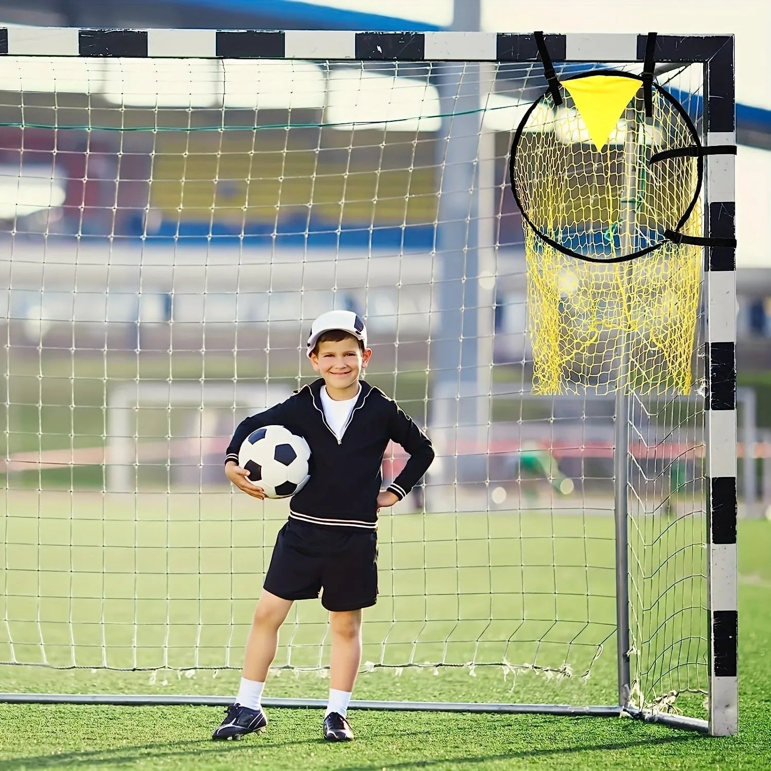 A portable black and yellow soccer training goal net with a steel frame set up on grass.