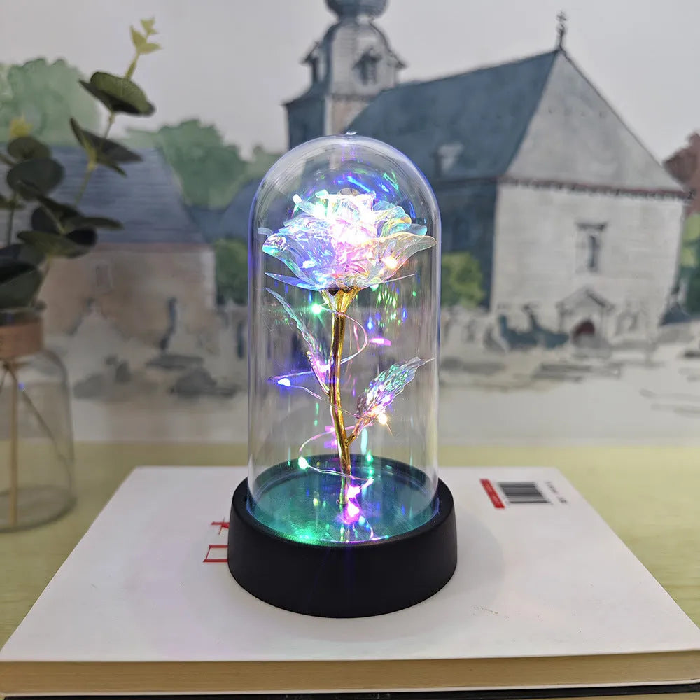 Small decorative night lamp with glass cover and plastic flowers, showing coloured light illumination.