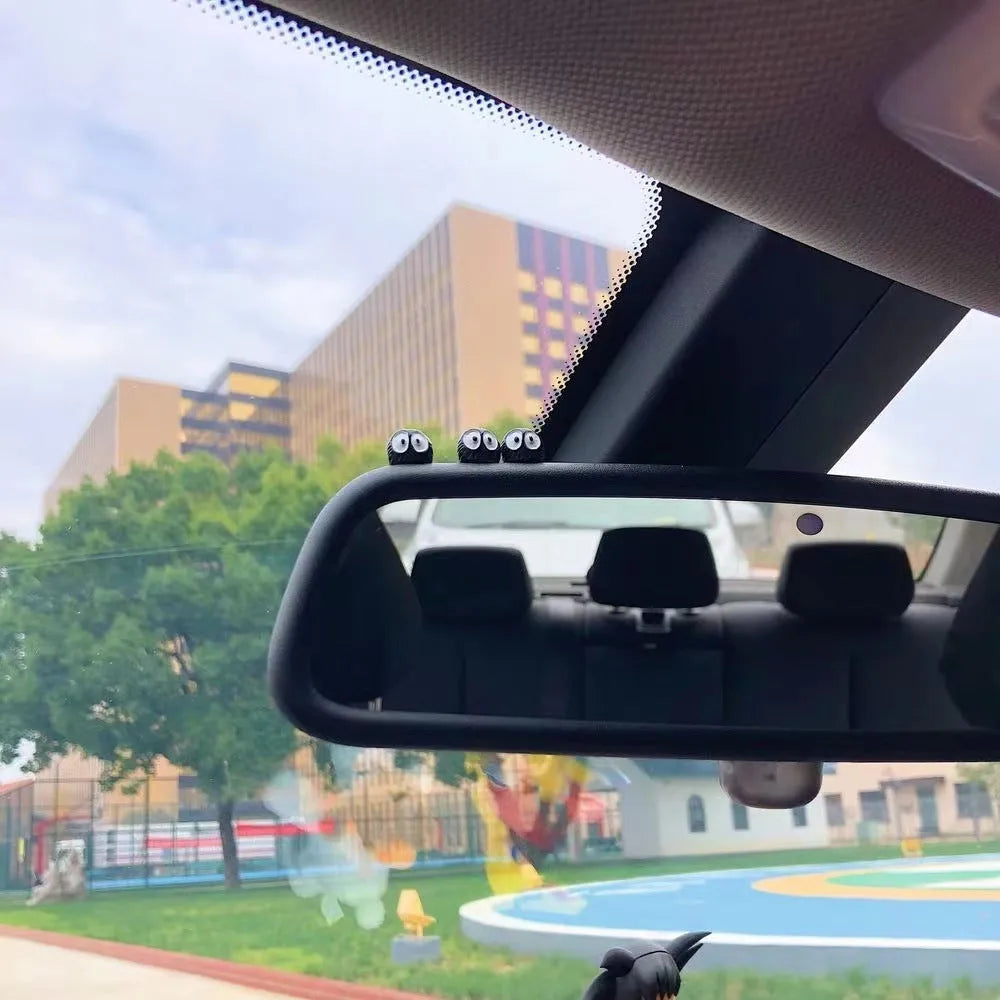 Small black resin coal ball cartoon decoration on a car dashboard.