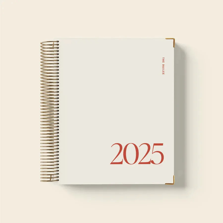 Cherry red coil-bound daily schedule notebook with spiral binding open on a desk