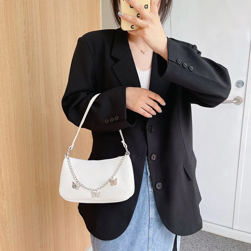Women's black butterfly chain underarm bag with crossbody strap, showing structured square shape and retro style.
