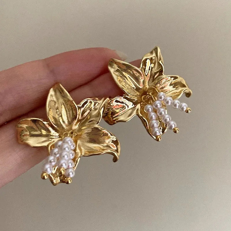 Gold H1795 pearl flower earrings with floral design on a white background.