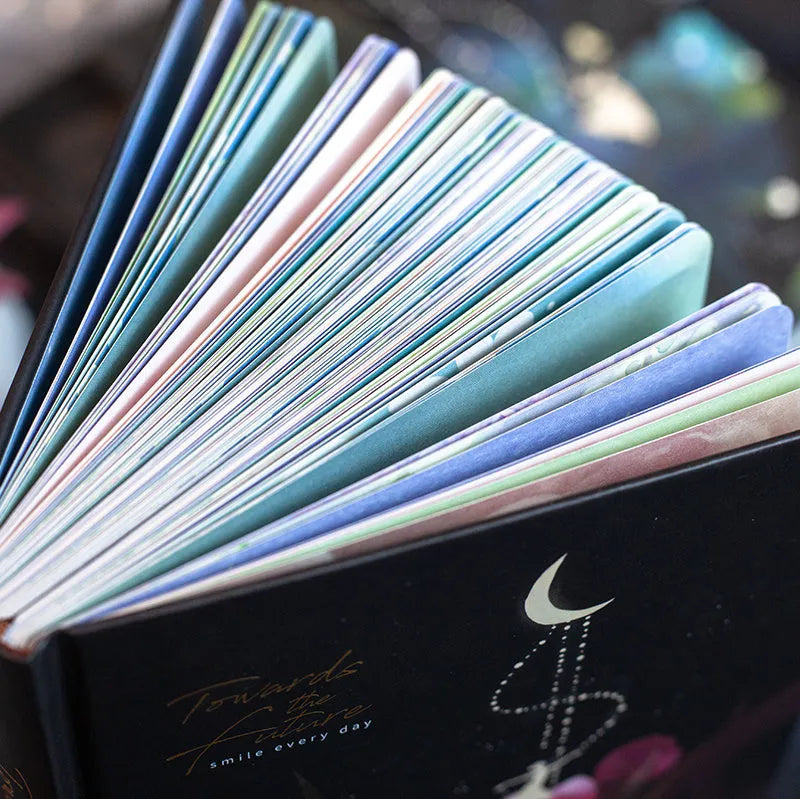 A5 notebook with luminous cover open to show colour illustrated pages, available in four colours.