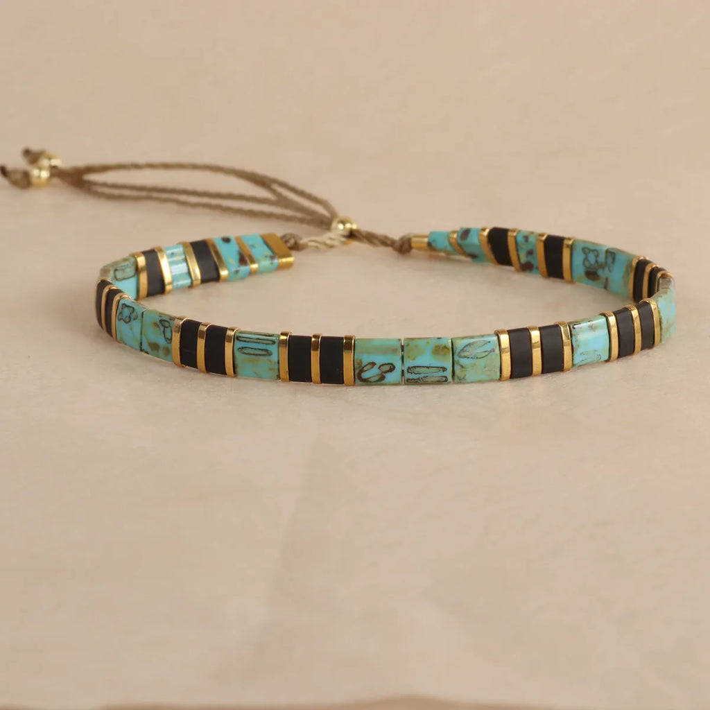 Geometric glass beaded bracelet in milky white, black, green, blue, or red on a white background.
