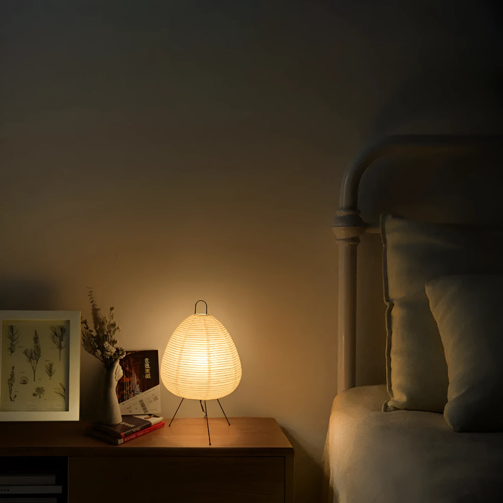 Japanese style table lamp with a white rice paper lantern shade and a silver aluminium base on a wooden table.