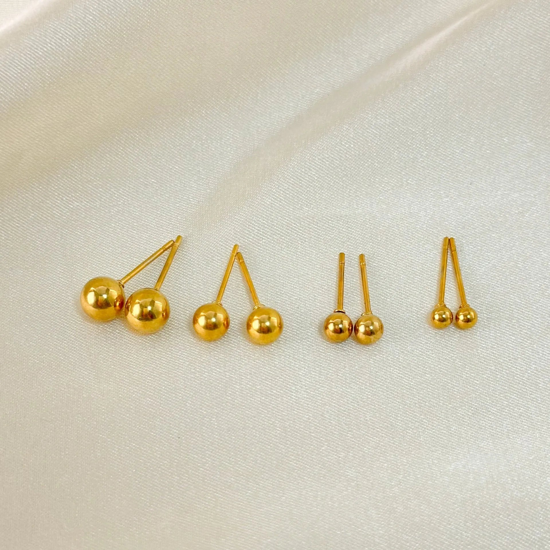 Gold and silver spherical ball stud earrings in 3mm, 4mm, 5mm, and 6mm sizes on a plain background.