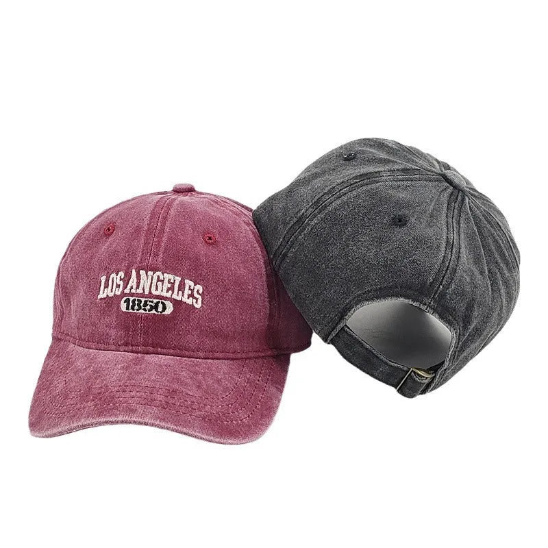 Retro style peaked cap with embroidered distressed letters on the front, shown in beige colour.