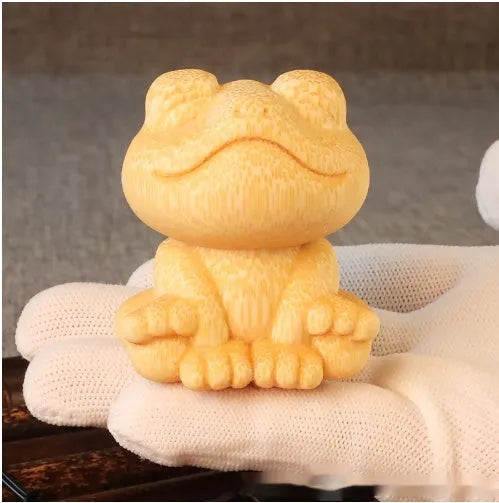 Solid bamboo carving ornament of a smiling frog cartoon character.