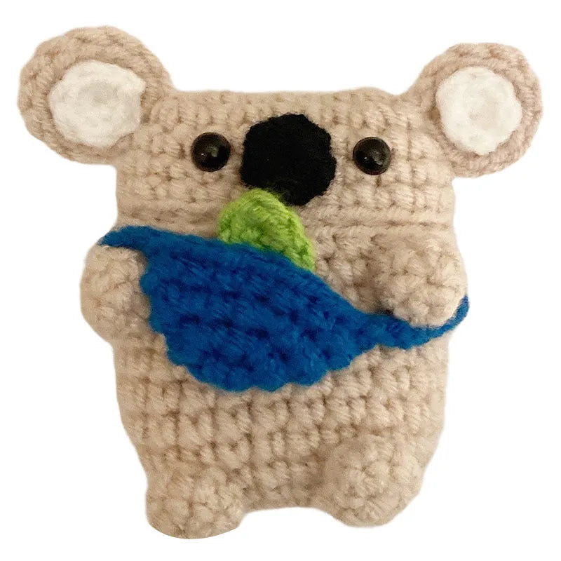 Handmade knitted koala bear backpack cover for AirPods charging case on a table.