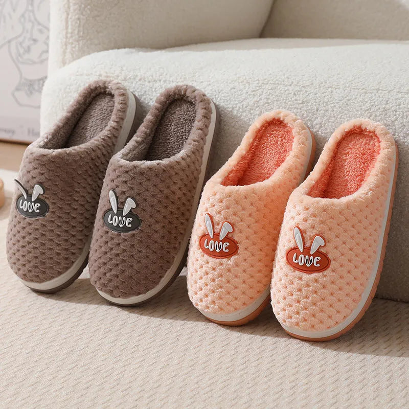 Women's plaid design artificial fur winter slippers with rubber sole on a wooden floor.