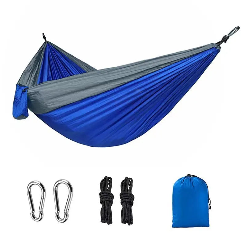Blue outdoor camping hammock made from parachute nylon fabric, hanging between two trees.