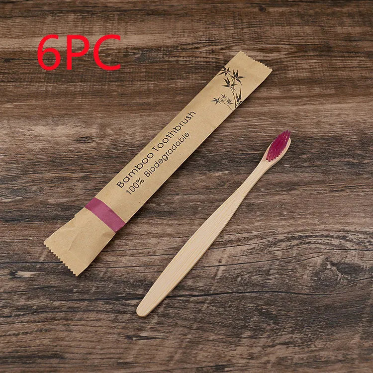Ten bamboo toothbrushes with coloured handles and charcoal bristles laid out side by side.