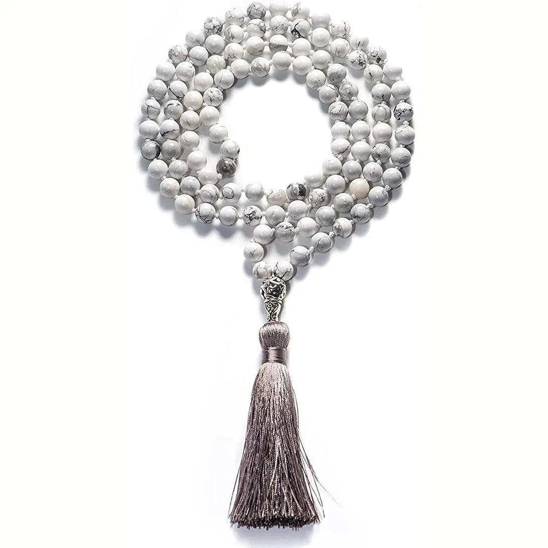Long blue patterned agate and stone tassel necklace with geometric beads on a white background.