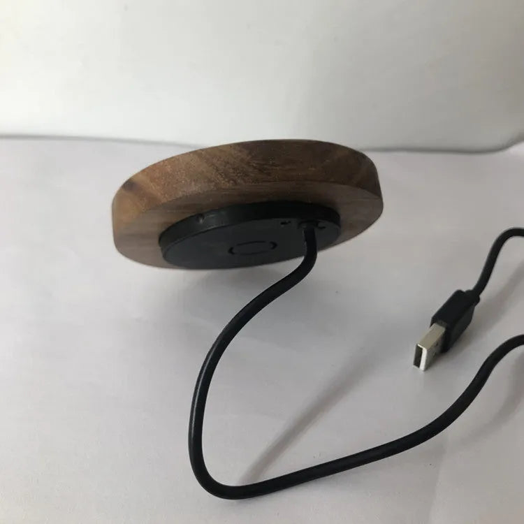 Black 75mm round wireless charging disc for embedding into desks, compatible with iPhone and Samsung phones.
