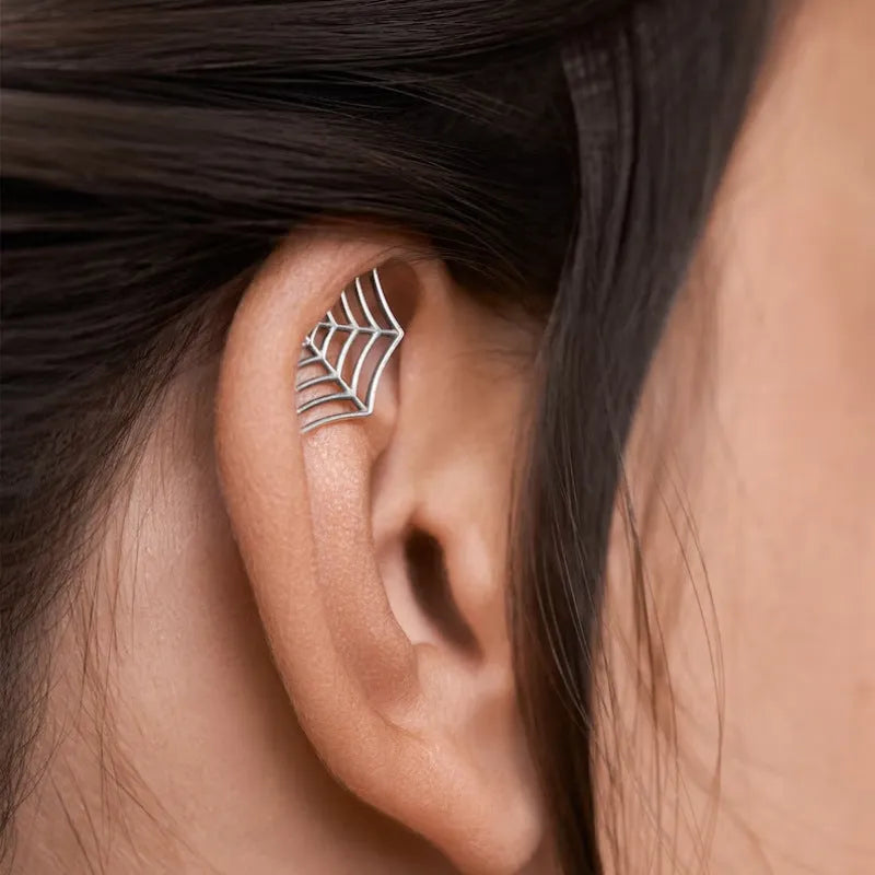 Close-up of metal spider web geometric mesh design stud earrings in a gold electroplated finish.