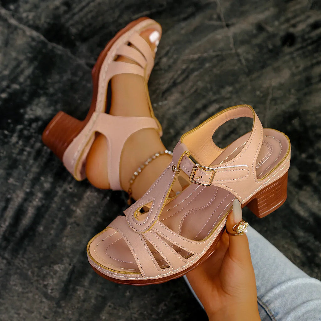 Women's black peep toe wedge sandals with a buckle fastening on a wooden floor.