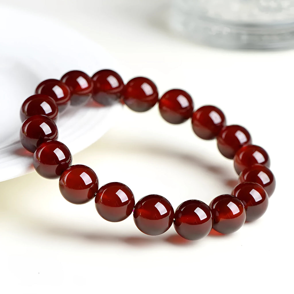 Natural Orange Red Garnet ball bracelet with a Ruyi charm on a white background