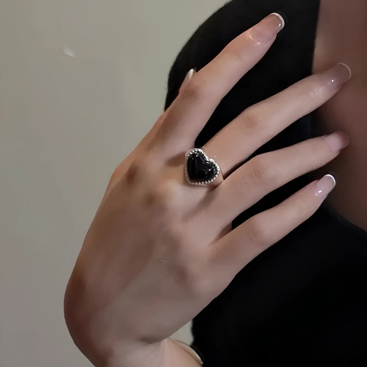 Sterling silver adjustable ring with black agate heart design on model's hand